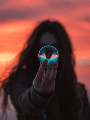 Woman with sunrise behind her holding crystal ball reflecting self worth Generative Change