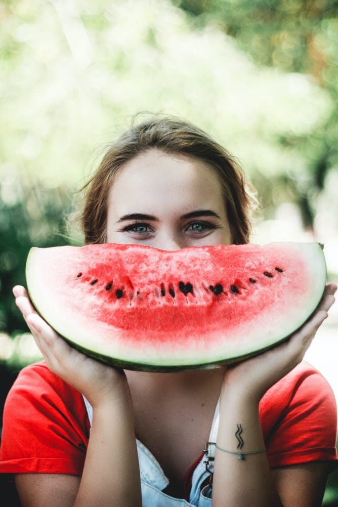 Healthy woman smiling behind watermelon slice boosting our immunity